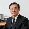 一位穿着深色西装、戴着无框眼镜的中年男性商务人士半身肖像照，背景是简约的办公室环境